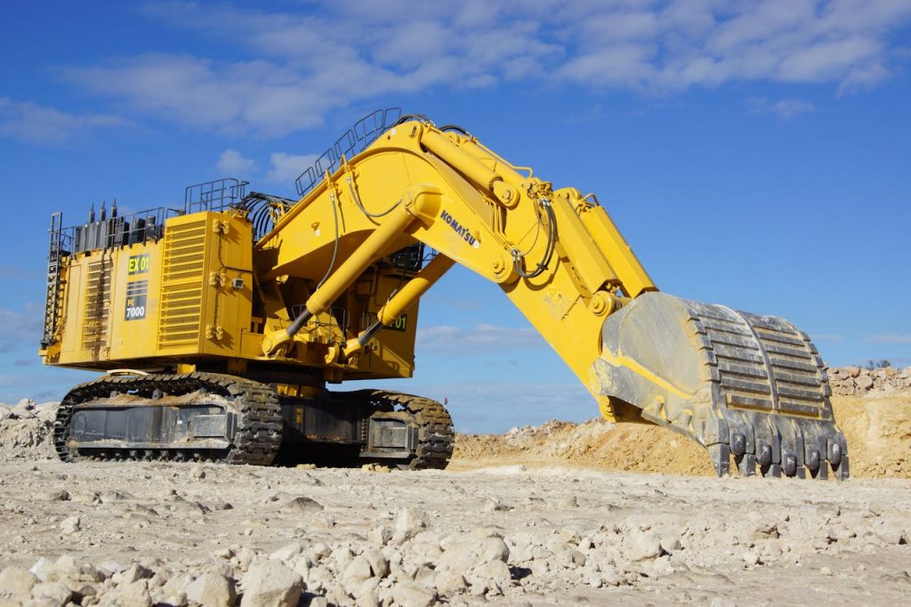 Equipment Inspections Heavy equipment inspection — yellow excavator at an open construction site under blue sky